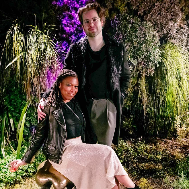 Two individuals engaged in a lively outdoor setting with vibrant greenery.